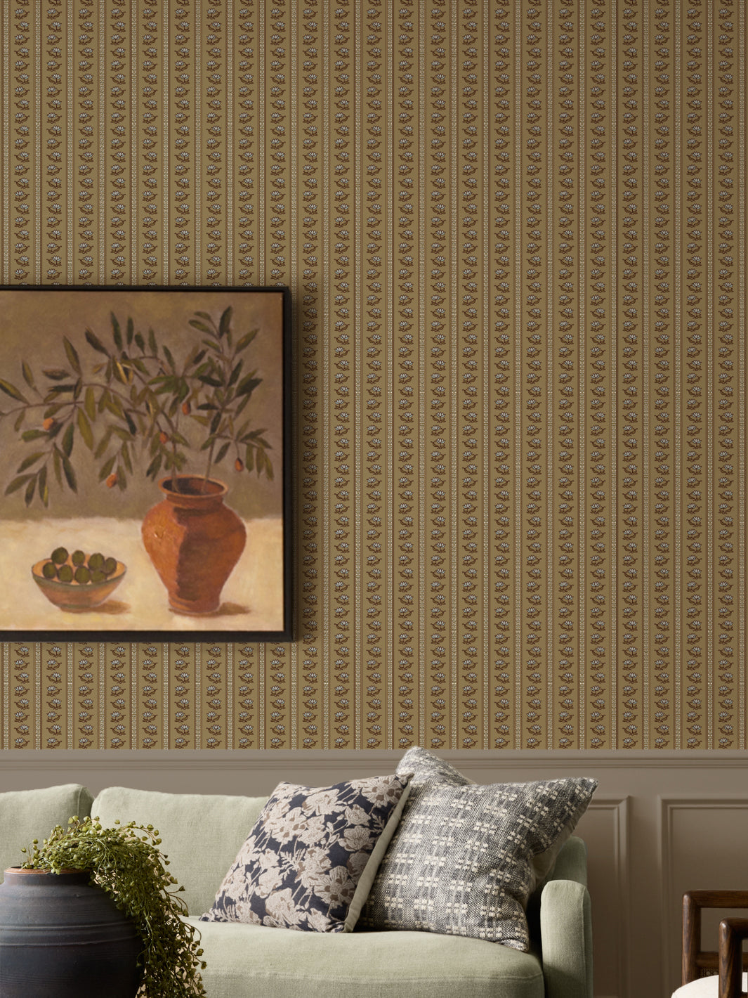 Aged Olive lotus stripe wallpaper above panelling with a sage sofa and a framed olive-branch still life