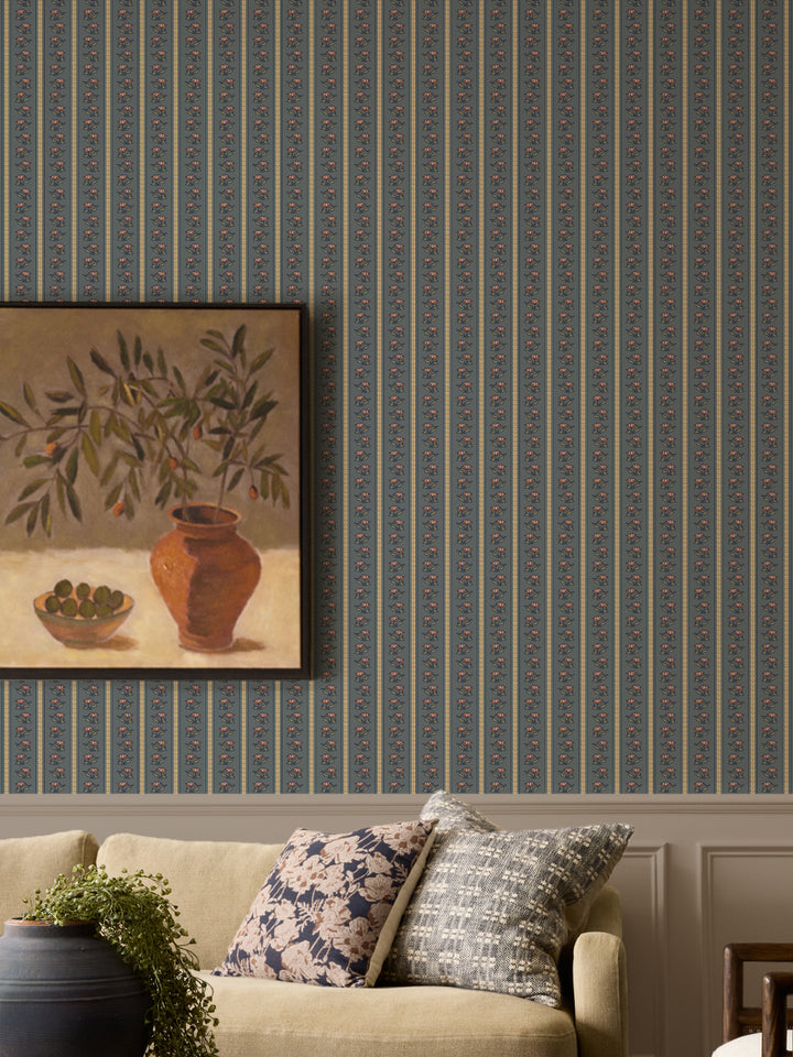 Slate blue lotus stripe wallpaper with an oatmeal sofa and a framed olive-branch still life