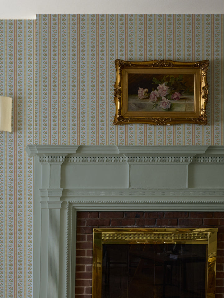 Powder blue lotus stripe wallpaper above a sage-painted mantel with a gilt-framed rose painting