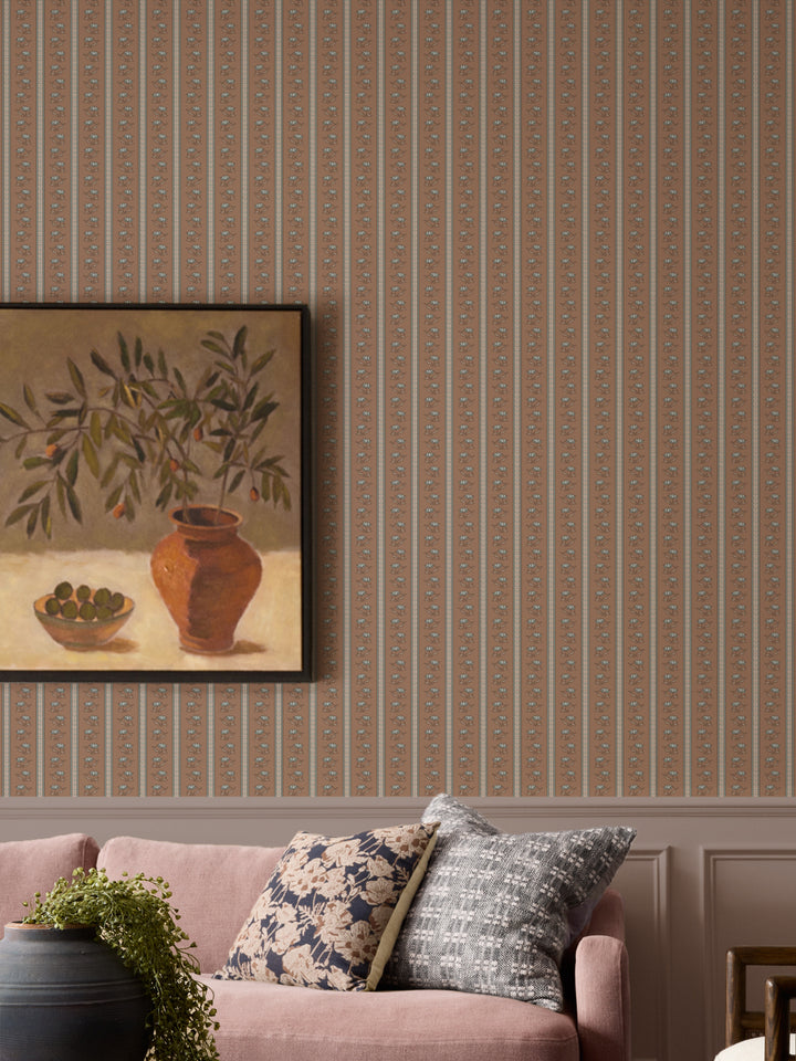 Brown lotus stripe wallpaper with a dusty pink sofa and a black urn holding a trailing plant