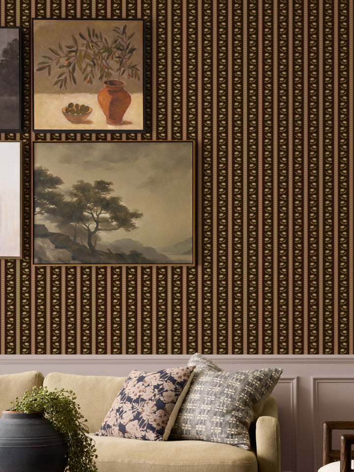Dark brown lotus stripe wallpaper on a gallery wall with two framed paintings and an oatmeal sofa