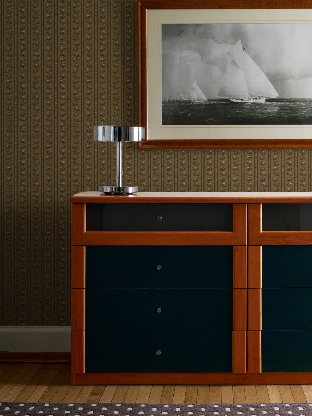 Olive lotus stripe wallpaper behind a cherrywood sideboard with teal drawers and a framed sailing print