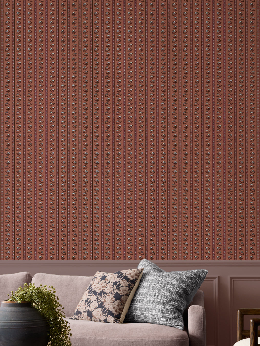 Terracotta lotus stripe wallpaper with a greige sofa and a black urn holding a trailing plant