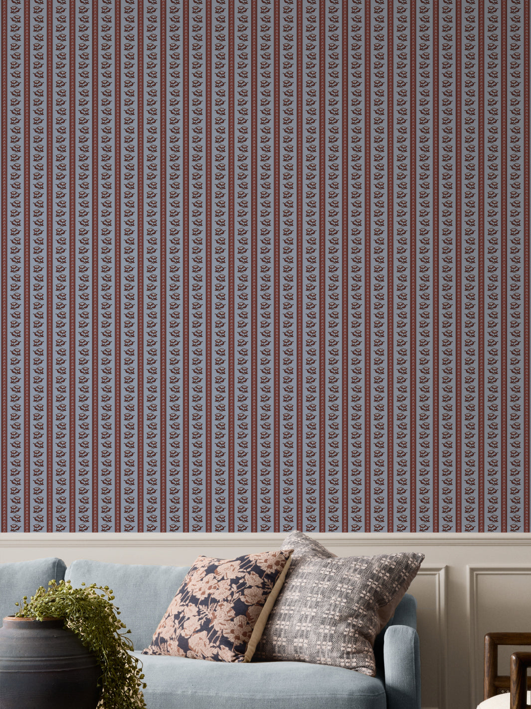 Periwinkle lotus stripe wallpaper with a light blue sofa and a black urn holding a trailing plant