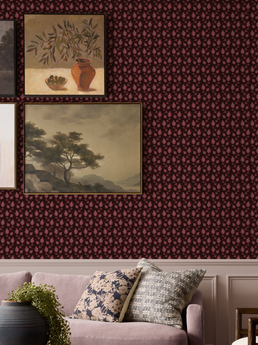 Framed still life and landscape paintings above a mauve sofa with floral and woven cushions