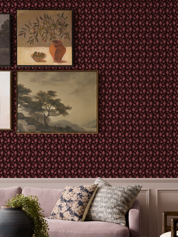 Framed still life and landscape paintings above a mauve sofa with floral and woven cushions