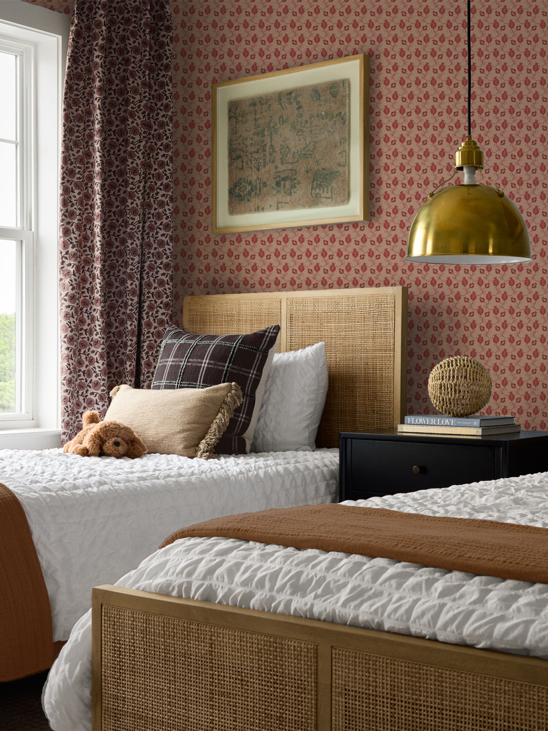 Cane headboard twin beds with white bedding, a teddy bear, black nightstand and brass pendant