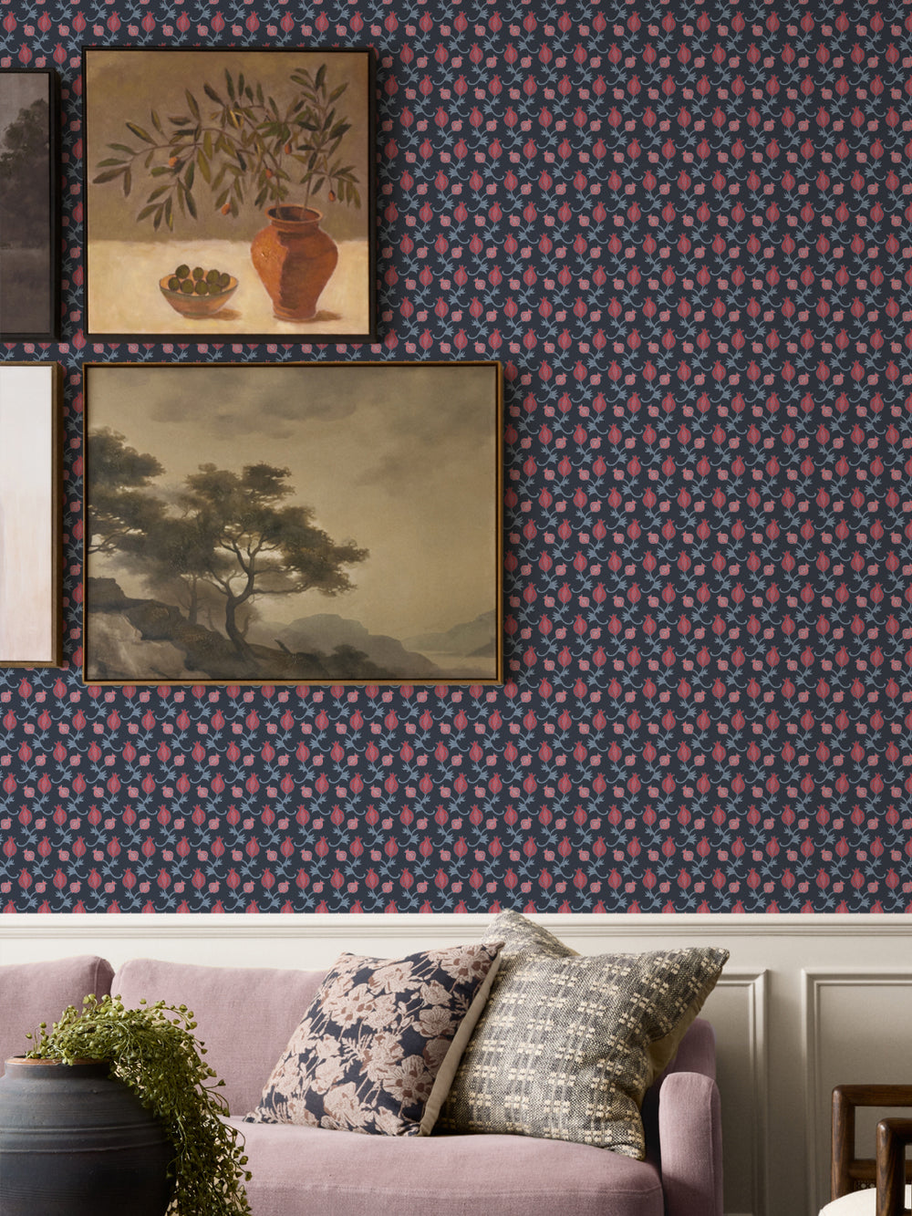 Two framed paintings above a mauve sofa with floral cushions and a black planter