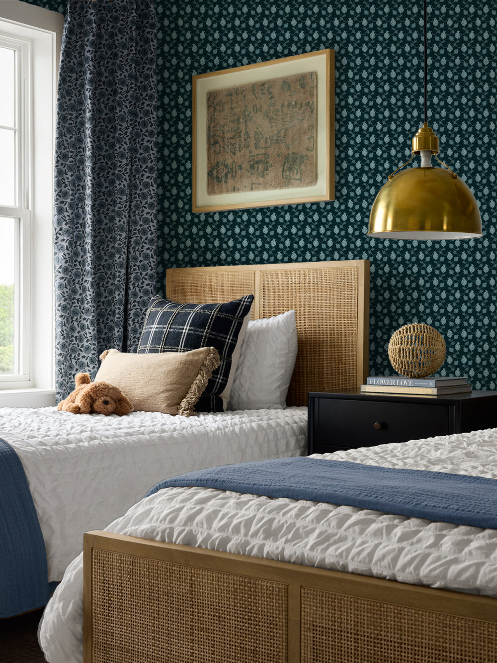Cane beds with a plaid cushion and blue throw, black nightstand and brass pendant lamp