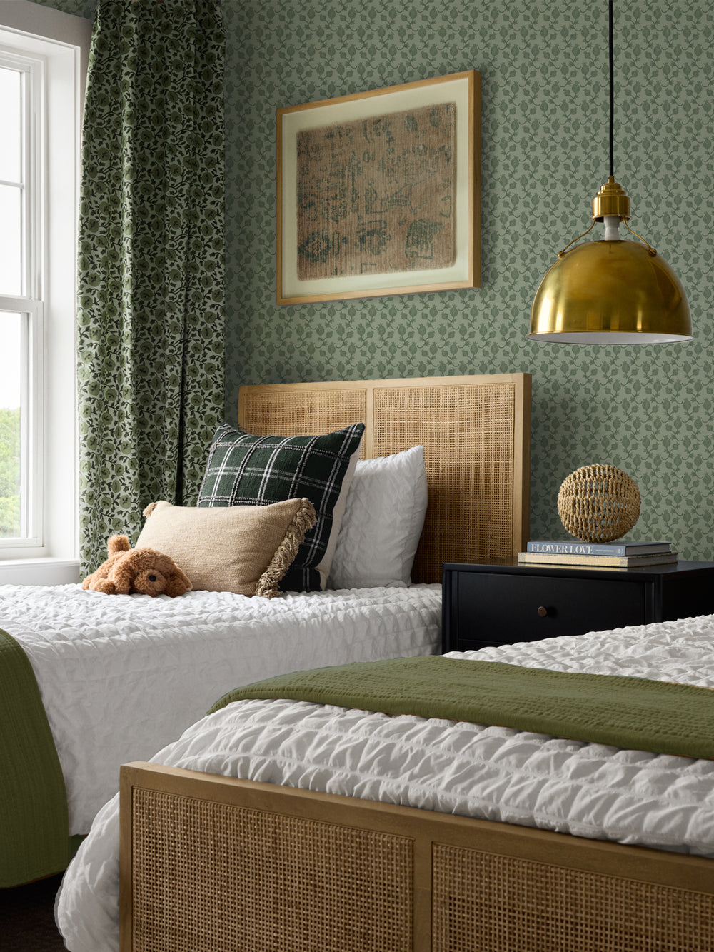 Cane beds with a green plaid cushion and olive throw, black nightstand and brass pendant