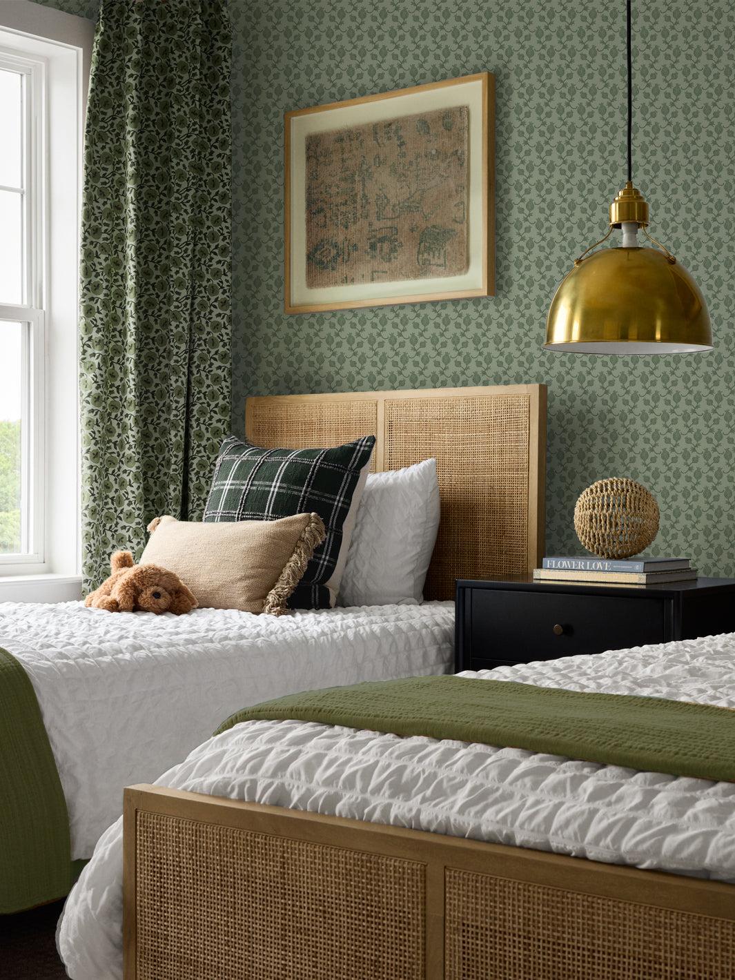 Cane beds with a green plaid cushion and olive throw, black nightstand and brass pendant