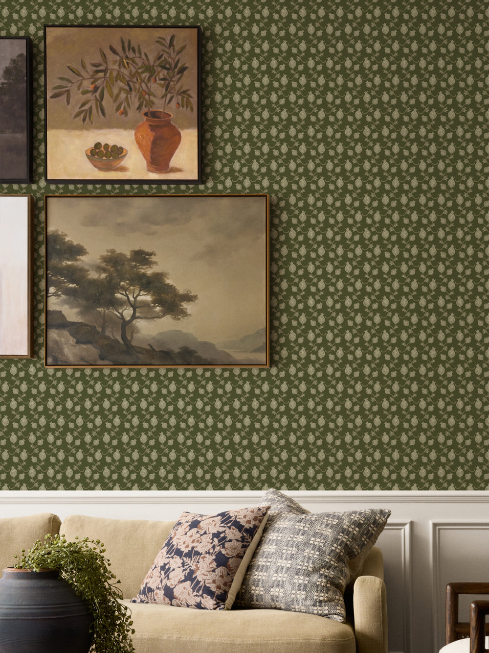 Framed still life and landscape above a tan sofa with floral cushions and a black planter