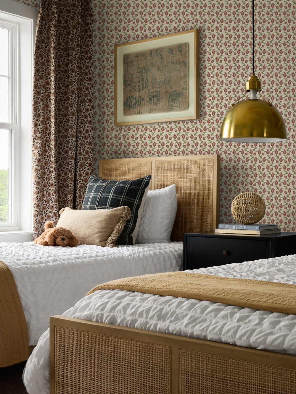 Cane bed with a green plaid cushion and mustard throw, black nightstand and brass pendant