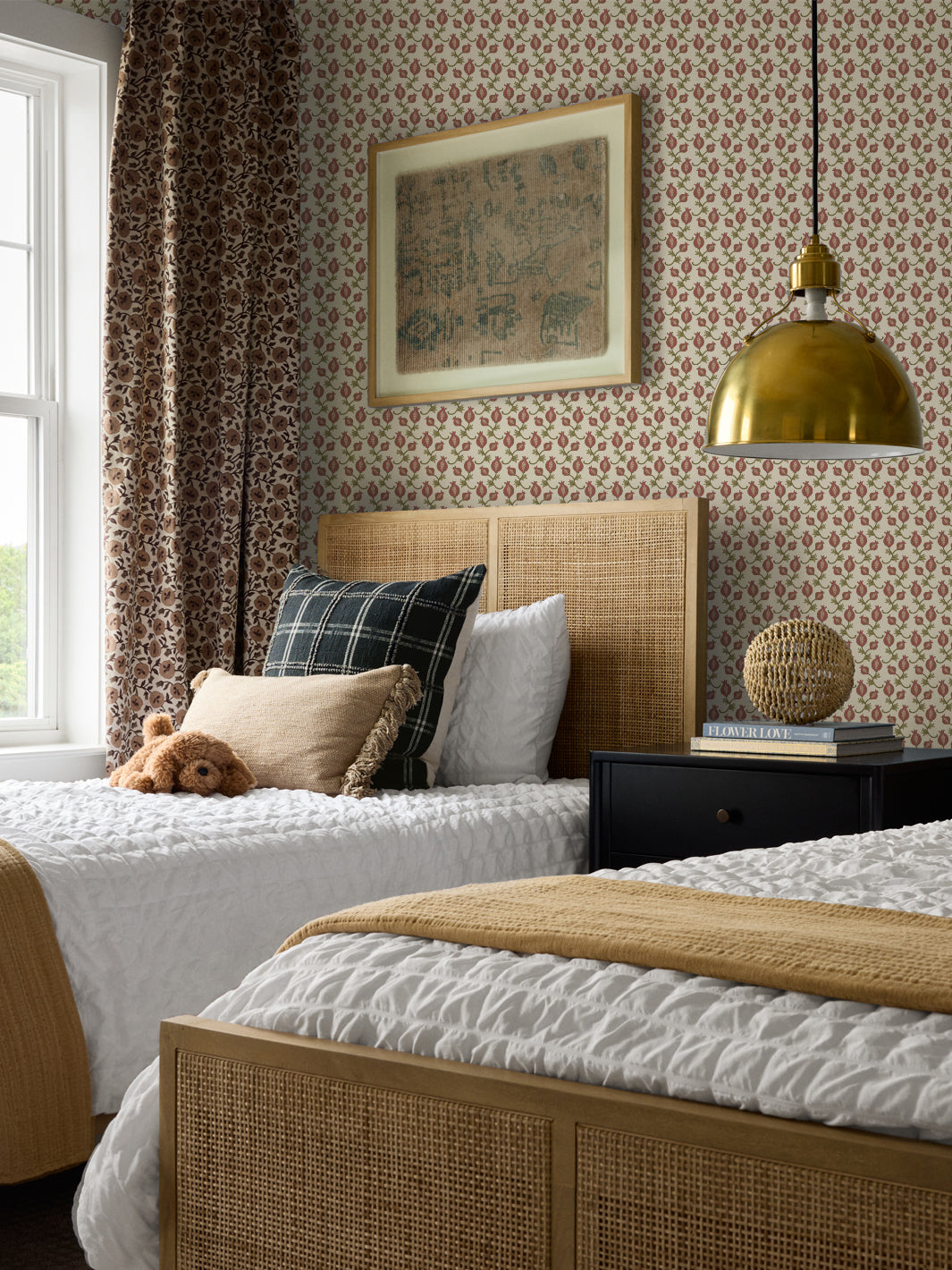 Cane bed with a green plaid cushion and mustard throw, black nightstand and brass pendant