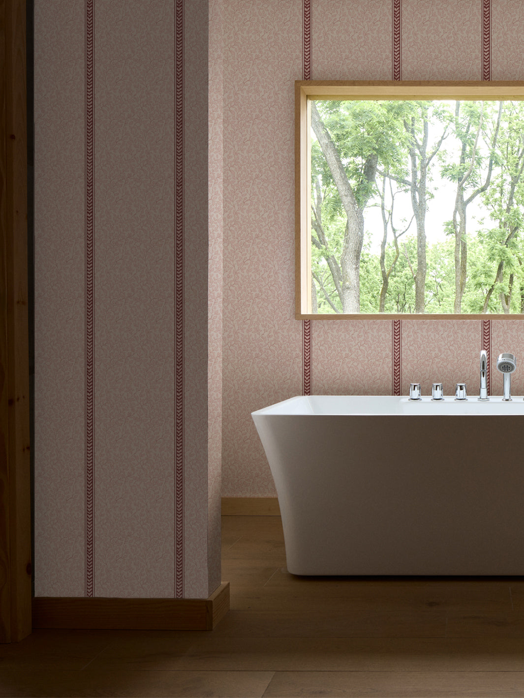 Bathroom with a white freestanding tub, chrome fixtures and a wood-framed window onto green trees
