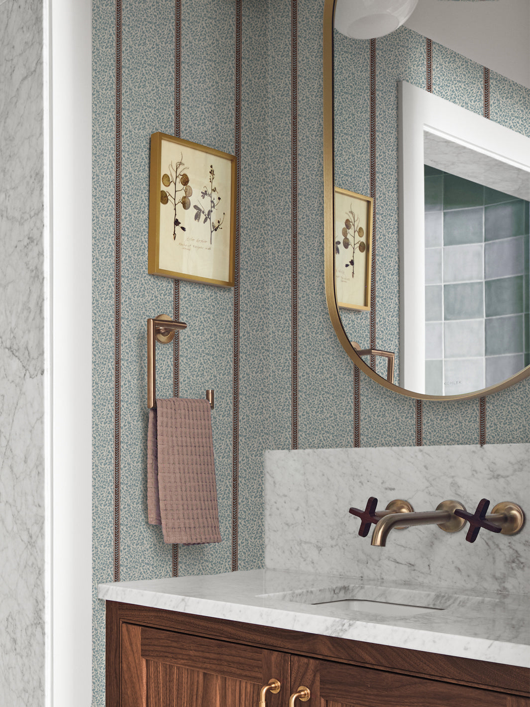 Powder room in blue vine wallpaper with walnut vanity, marble counter, brass faucet and arched mirror