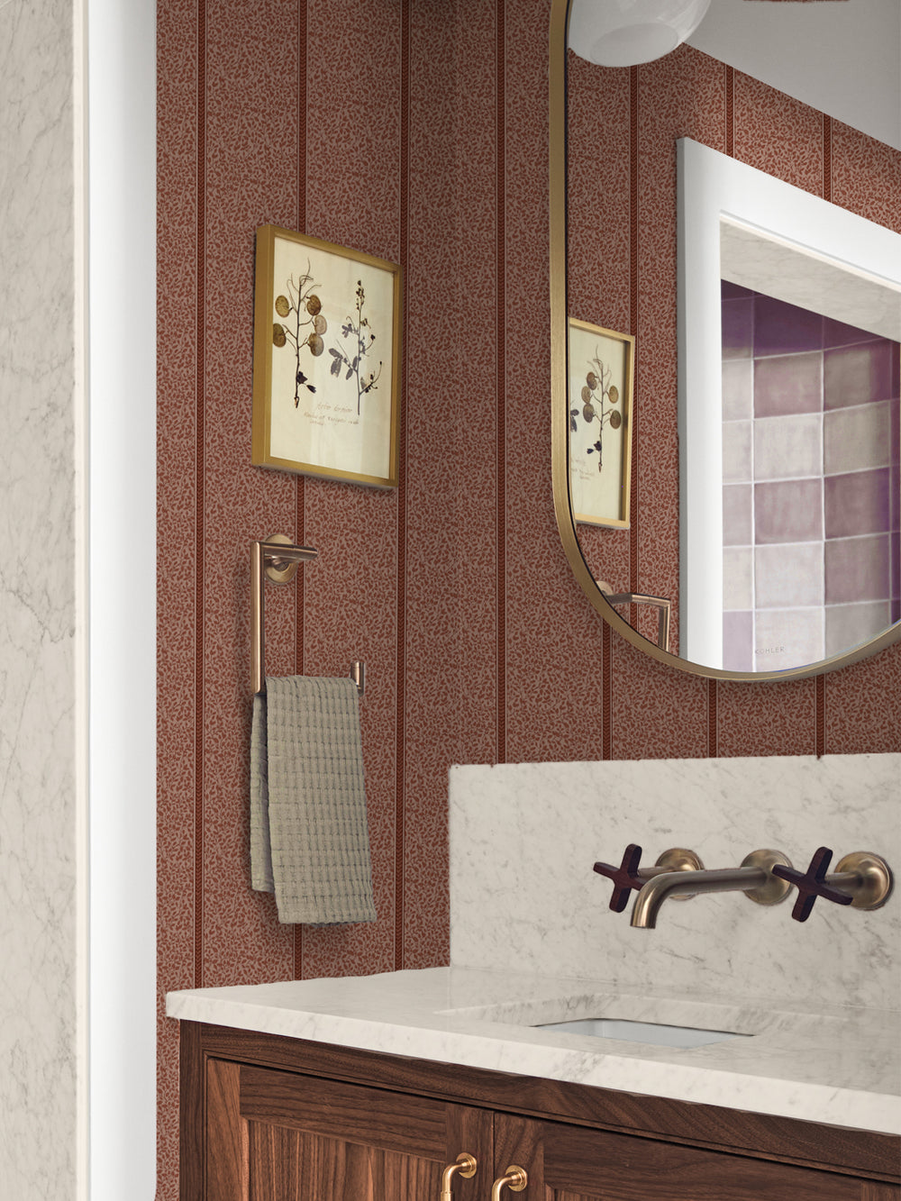 Powder room in rust vine wallpaper with a marble sink, brass fixtures and framed botanical art