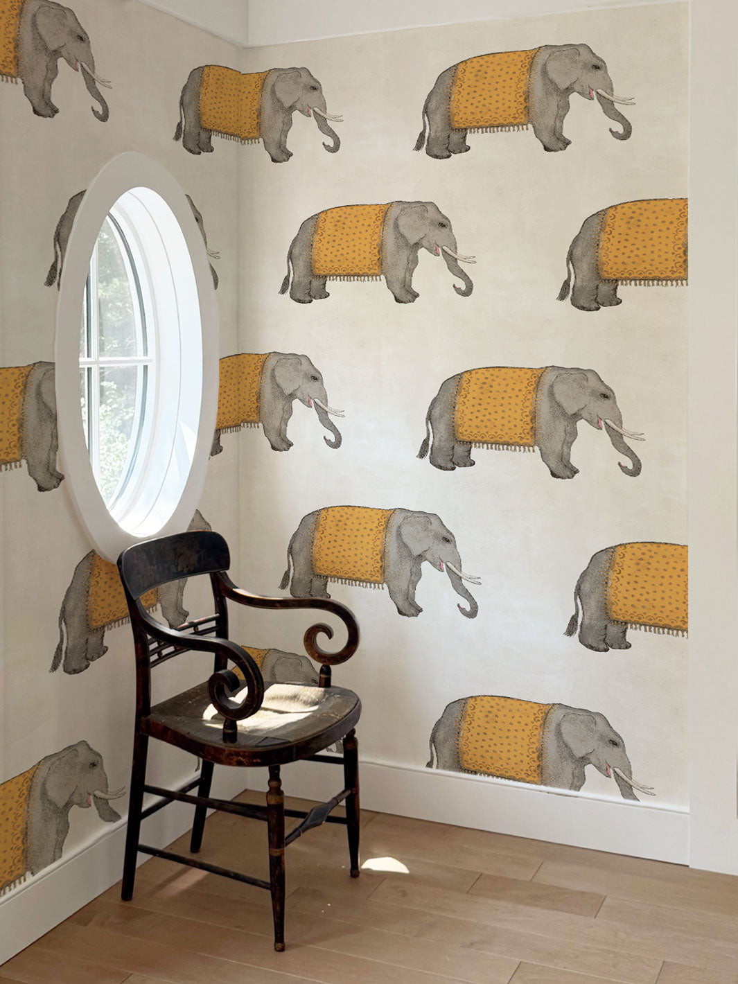 Elephant wallpaper on wall with gray elephants and orange blankets; chair and window visible