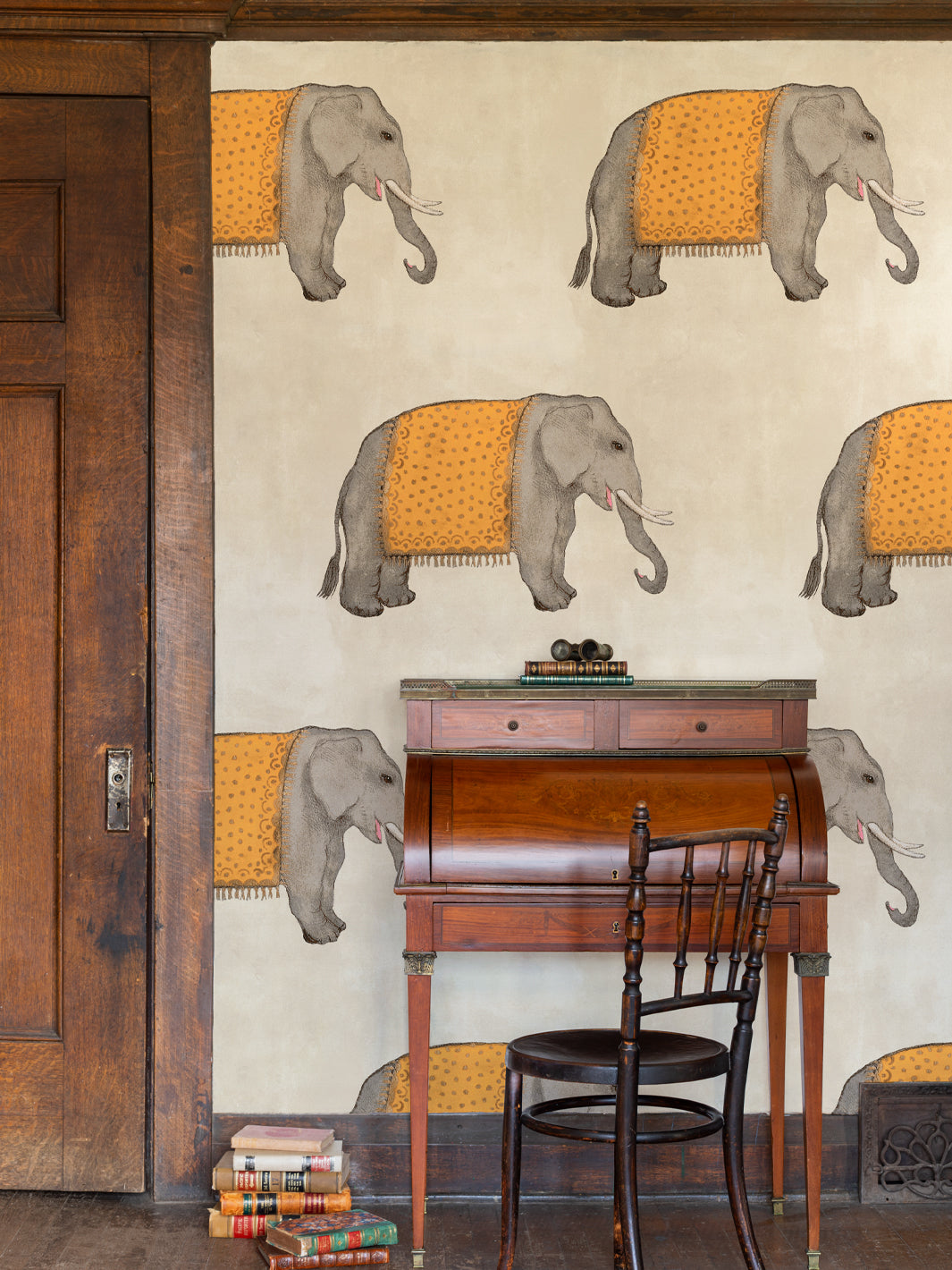 Elephant wallpaper pattern with several gray elephants wearing orange fringed cloth