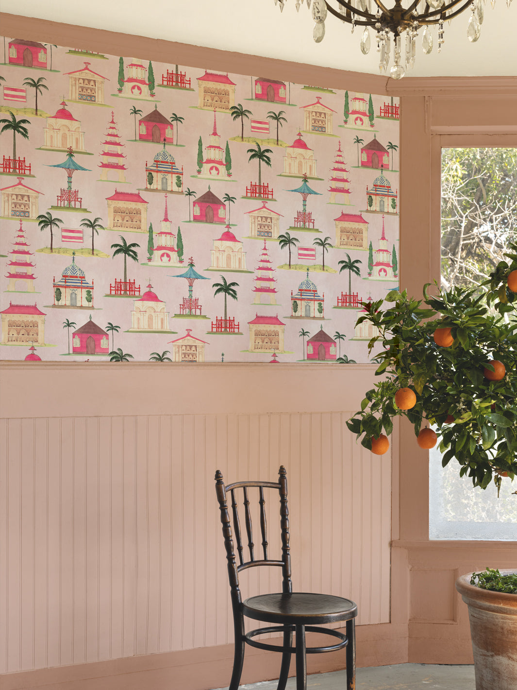 Blush pink wallpaper on wall with repeating pagoda pattern in red, green and teal