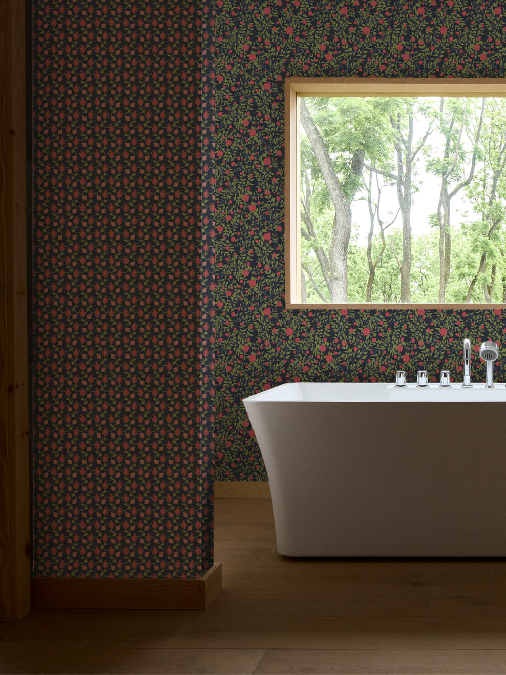 White freestanding tub and chrome faucet by a window, navy paper with green leaves and pink fruit