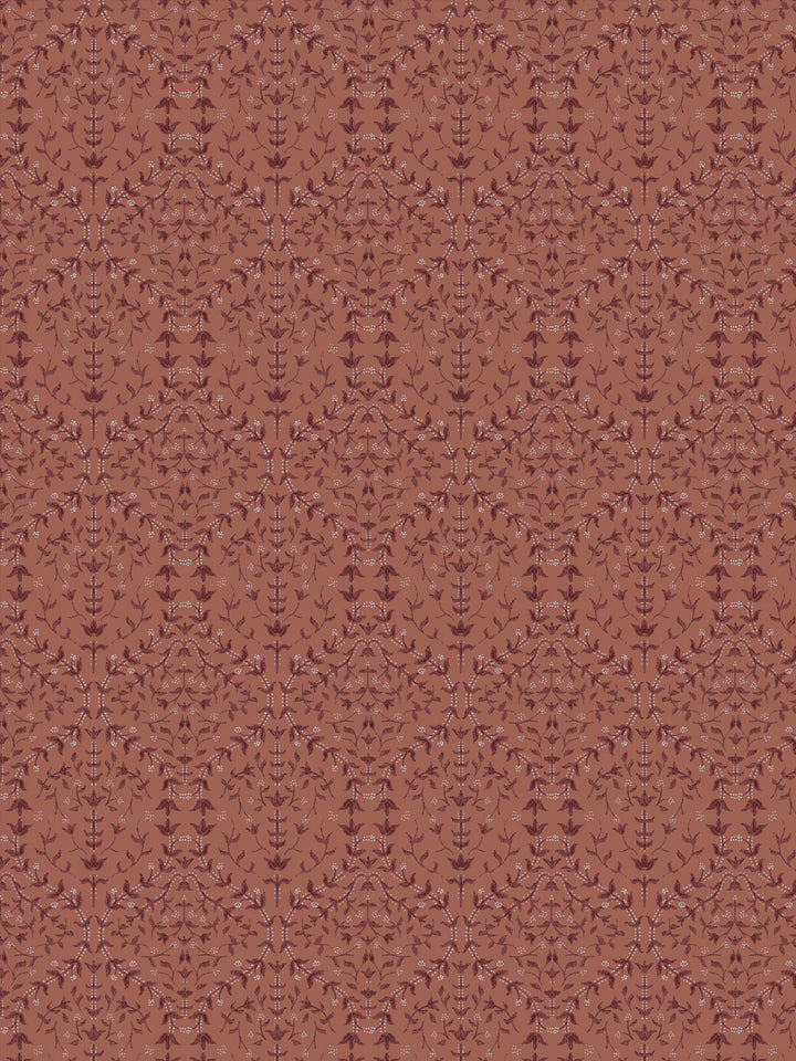 Close crop of deeper maroon-brown lily sprigs on muted terracotta clay