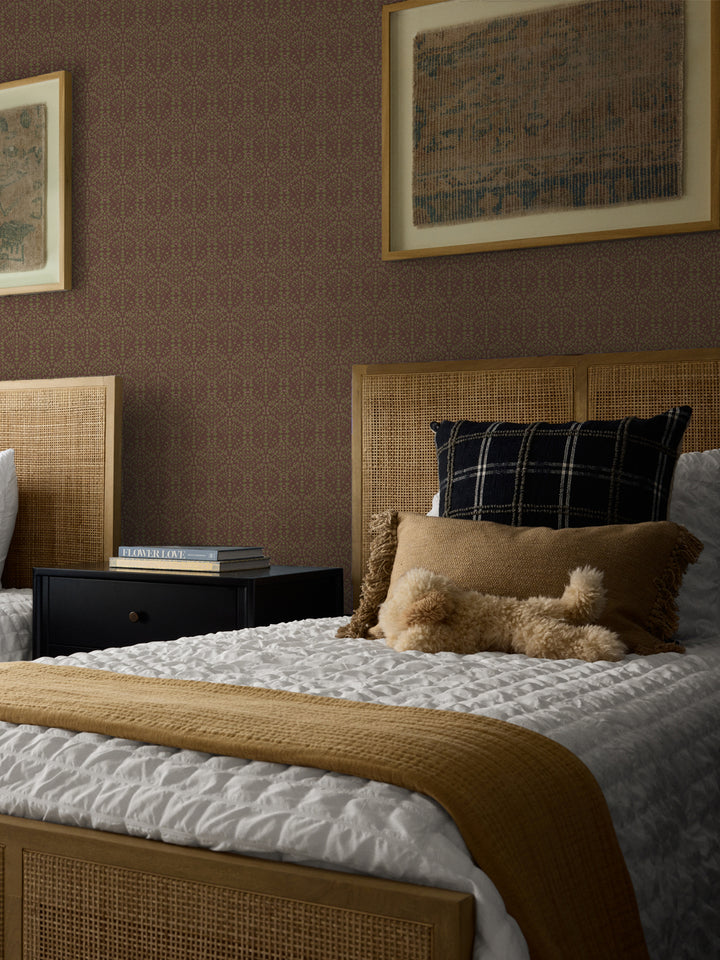 Mauve-brown Liliana wallpaper in a bedroom with cane headboards and framed antique textiles