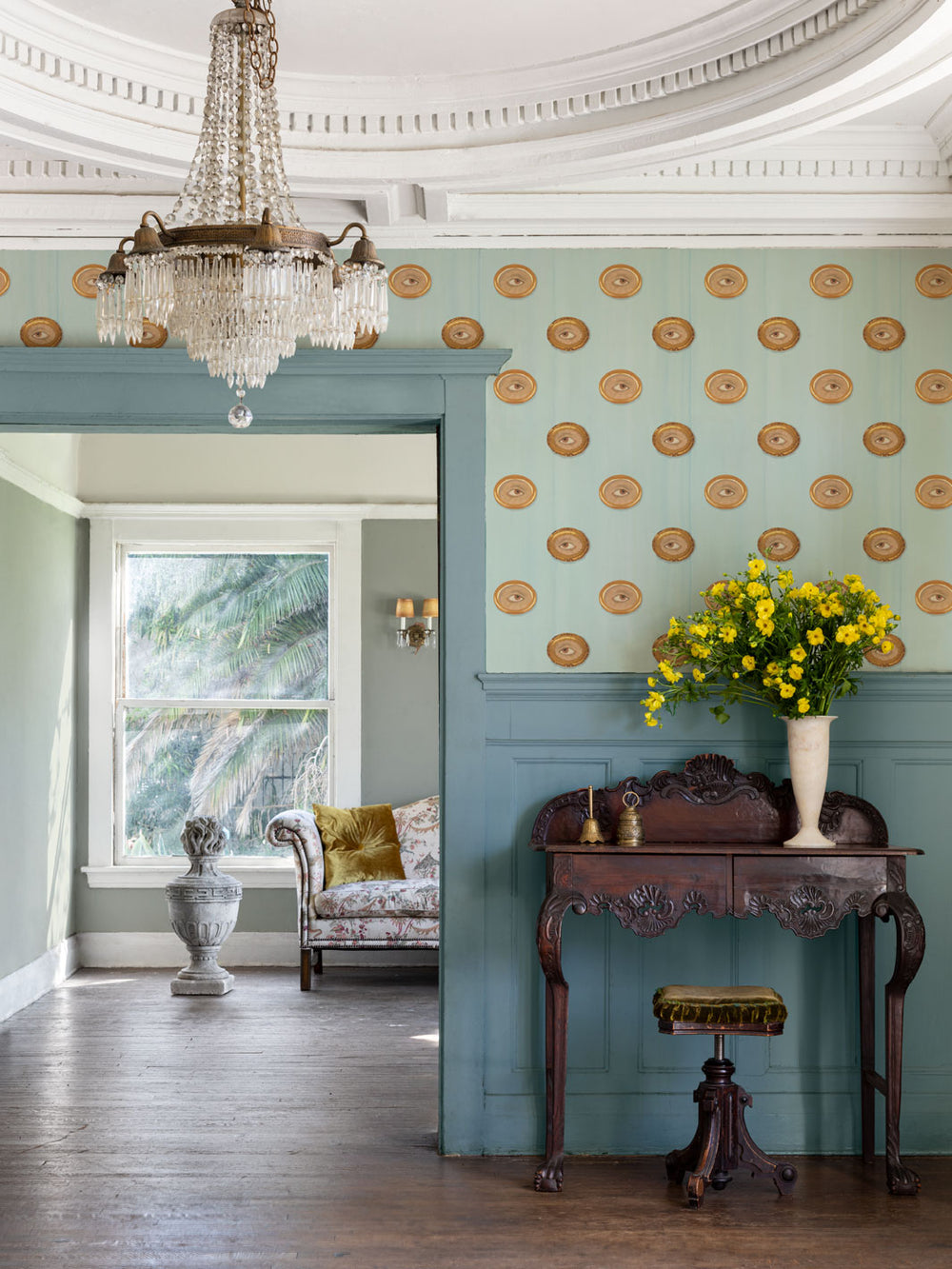 Brown eye motif wallpaper with gold-framed oval eyes on light blue wall