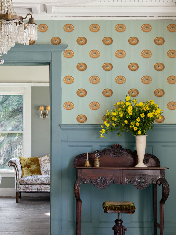 Wallpaper on wall with repeating gold oval eyes and green irises pattern