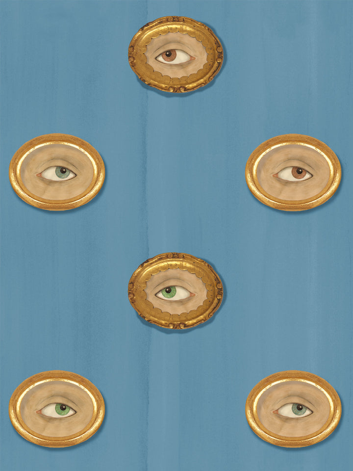 Dusty steel blue wallpaper with gilt oval frames holding painted eyes in brown, green and blue-gray