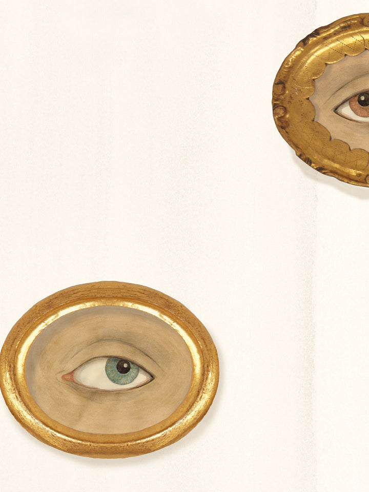 Close-up of ivory wallpaper showing a gold oval frame around a painted sea-green eye