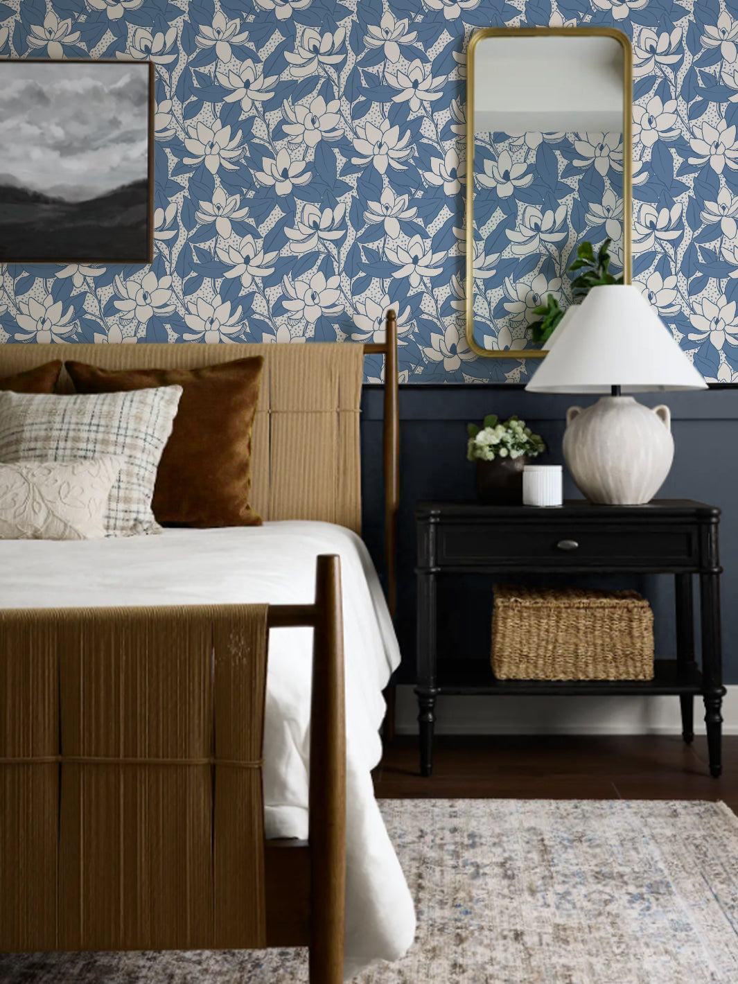 Cornflower Magnolias wallpaper above navy wainscot in a bedroom with rush bed and gold mirror