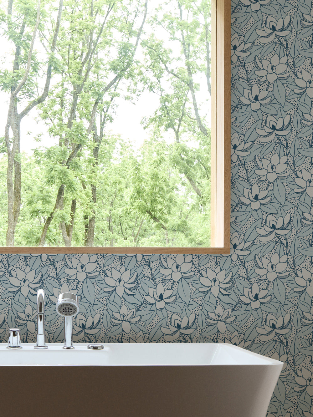 Glacier Navy Magnolias wallpaper in a bathroom with white freestanding tub and oak-framed window