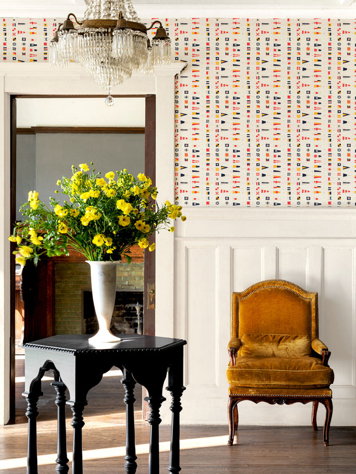 Nautical flag wallpaper covering a wall, with chair and table in foreground