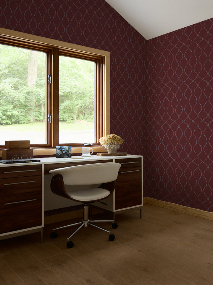 Merlot trellis wallpaper in a study with a walnut desk, white swivel chair and dried hydrangeas