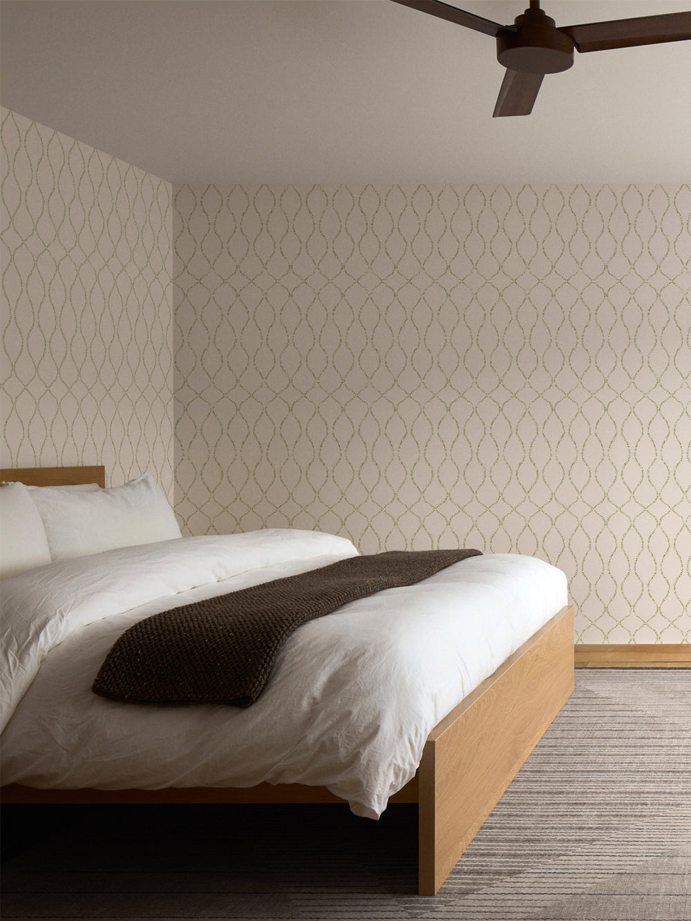 Cream and olive trellis wallpaper behind an oak bed with a white duvet and grey striped rug