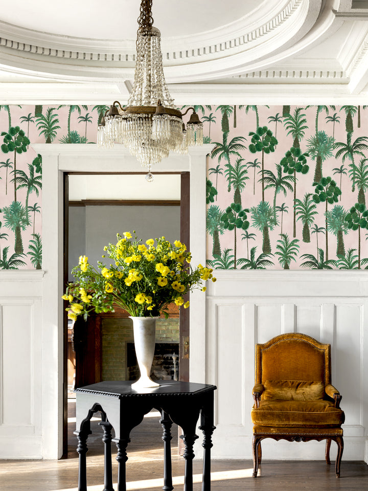 Palm tree wallpaper covering the room walls, green foliage on blush pink background