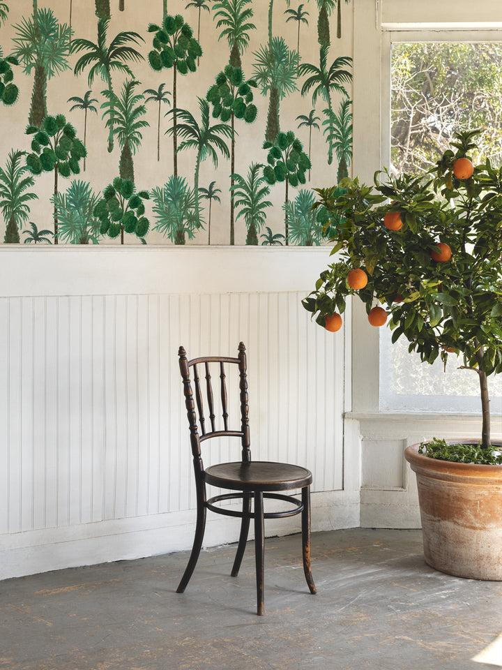 Tropical palm tree wallpaper covering wall in green on light parchment.