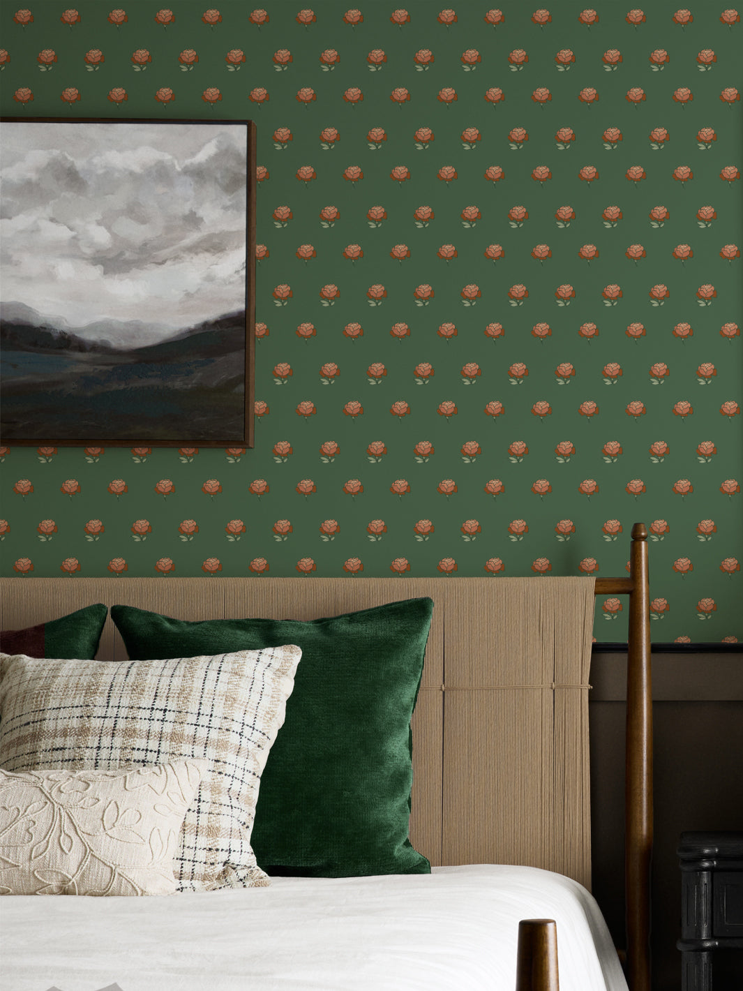 Bedroom wall in green peony wallpaper behind a rattan headboard with a framed landscape