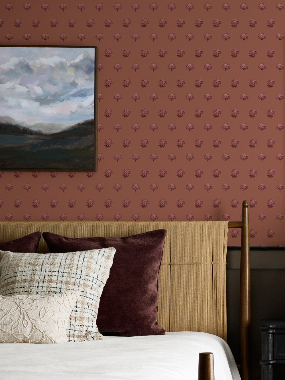 Bedroom wall in tonal rose and clay peony wallpaper with a cane headboard and cloud landscape