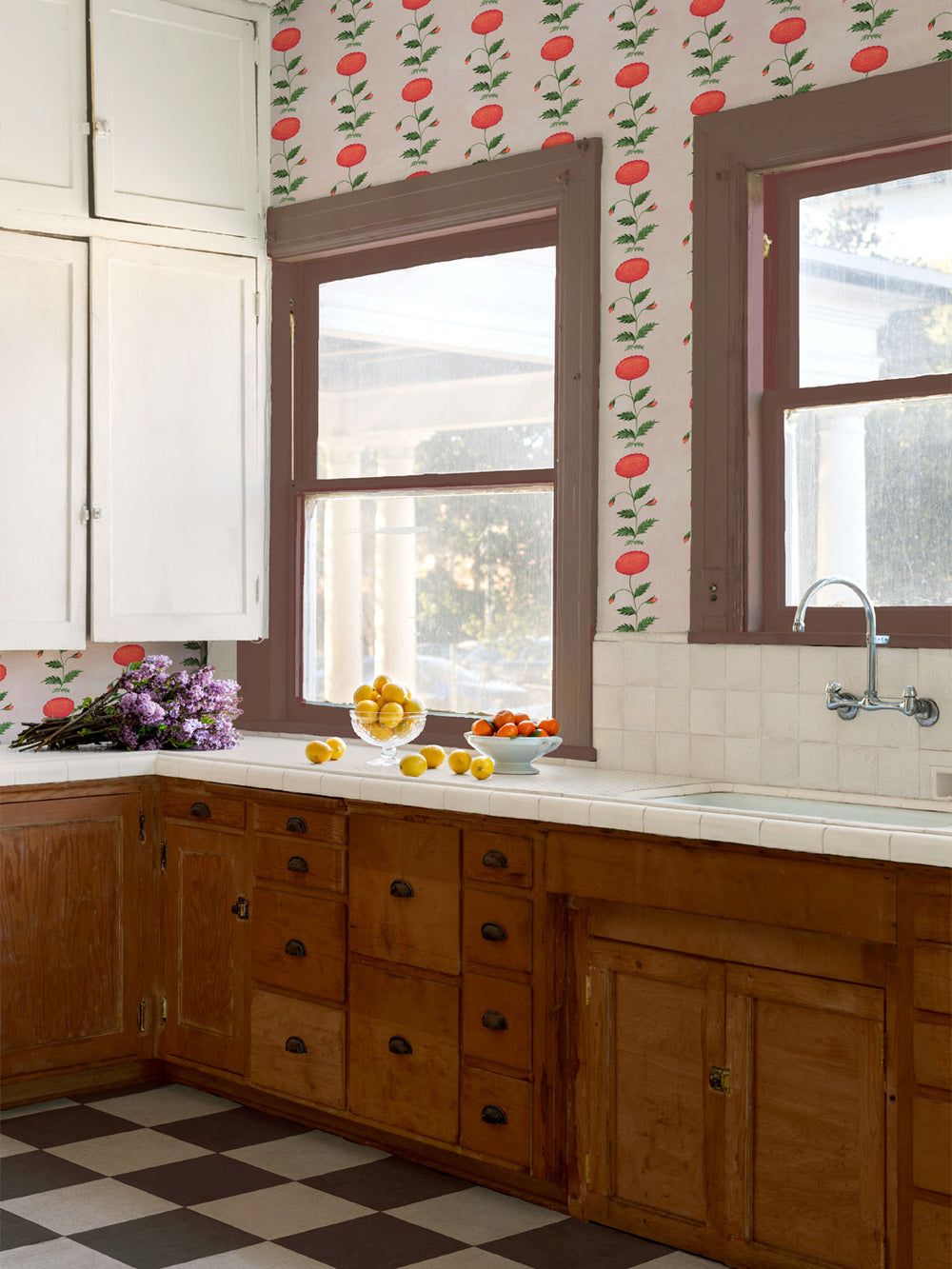 Floral wallpaper in a room with repeating red blooms and green foliage.