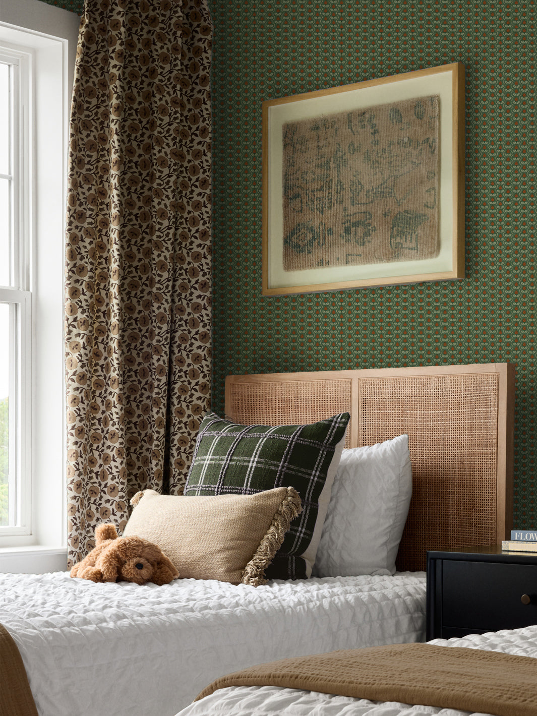 Forest green Pomara Bloom wallpaper in a bedroom with a cane headboard and green plaid pillow