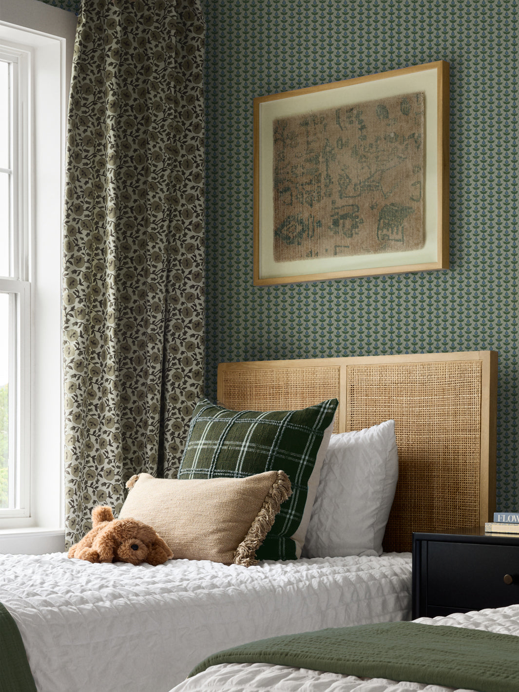 Grey-green Pomara Bloom wallpaper in a bedroom with a cane headboard and olive curtain