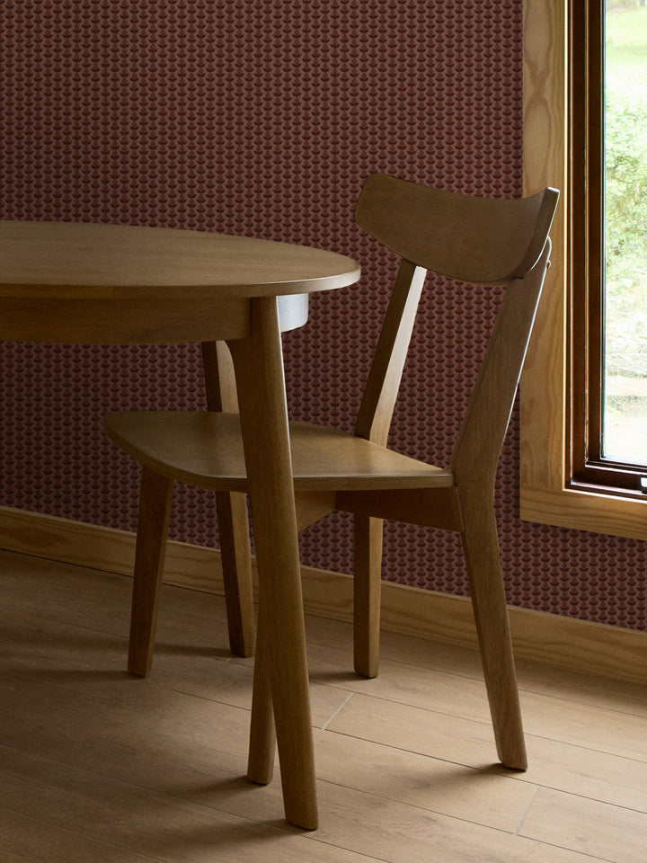 Terracotta and wine Pomara Bloom wallpaper behind a round oak dining table and chair