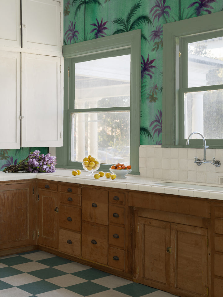 Green tropical palm leaf wallpaper covering the wall behind windows