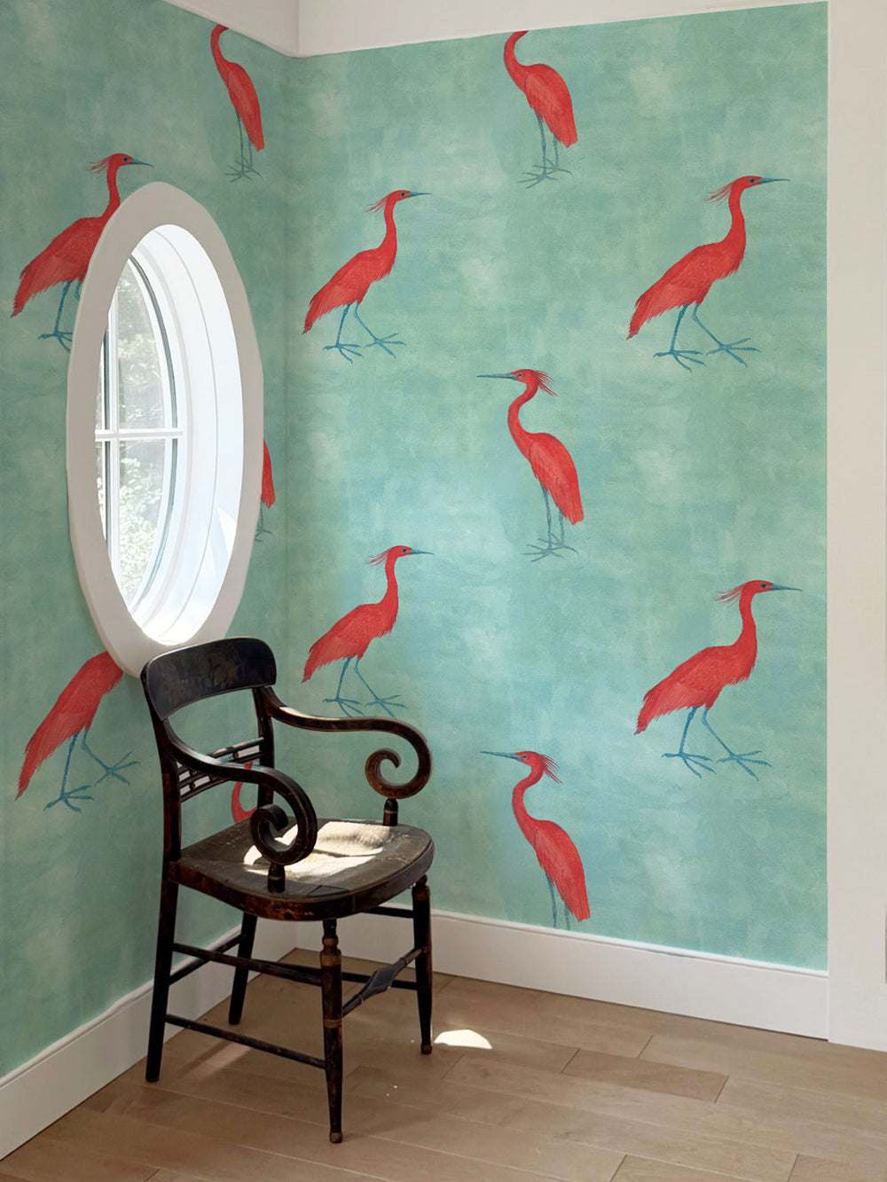 Aqua blue wallpaper with repeating red egret birds pattern in a room corner