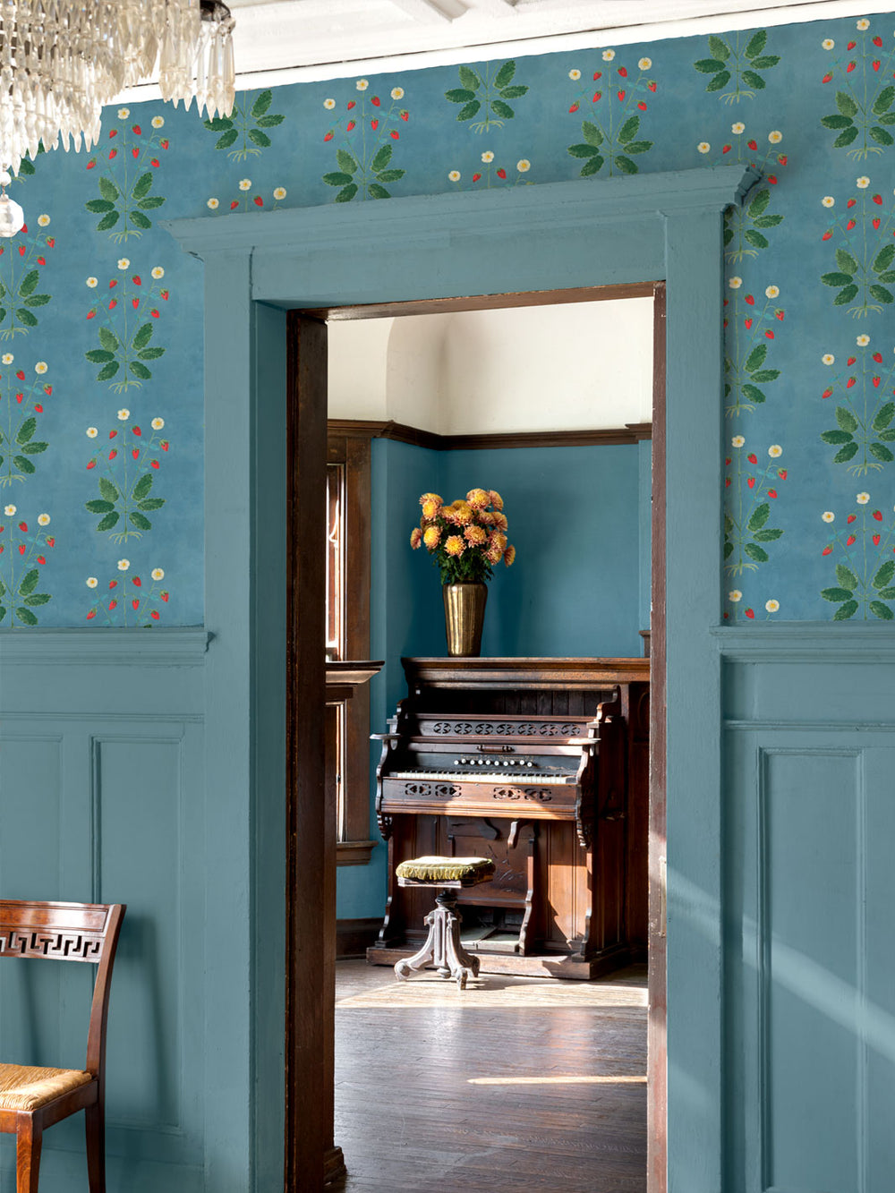 Botanical wallpaper around doorway with blue background, red strawberries, and cream blossoms.