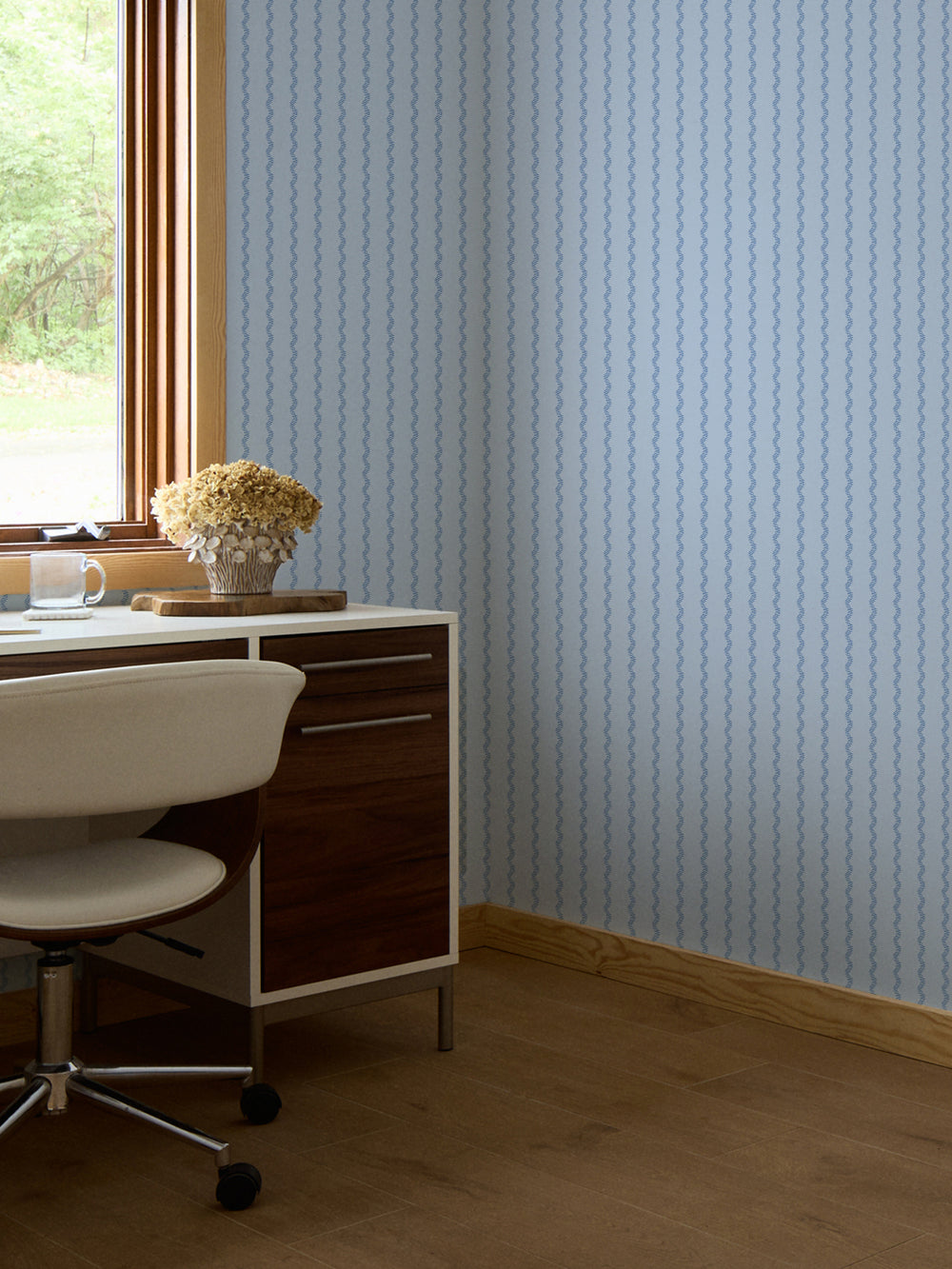 Powder blue stripe wallpaper in a home office with walnut desk and dried hydrangeas