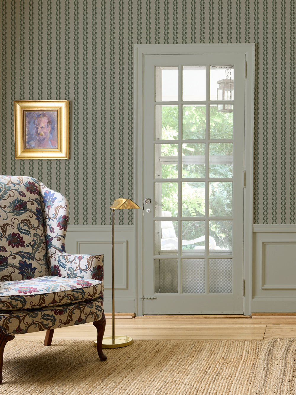 Aged Olive Sutton Vine wall with a floral wingback chair, brass floor lamp and sage French door