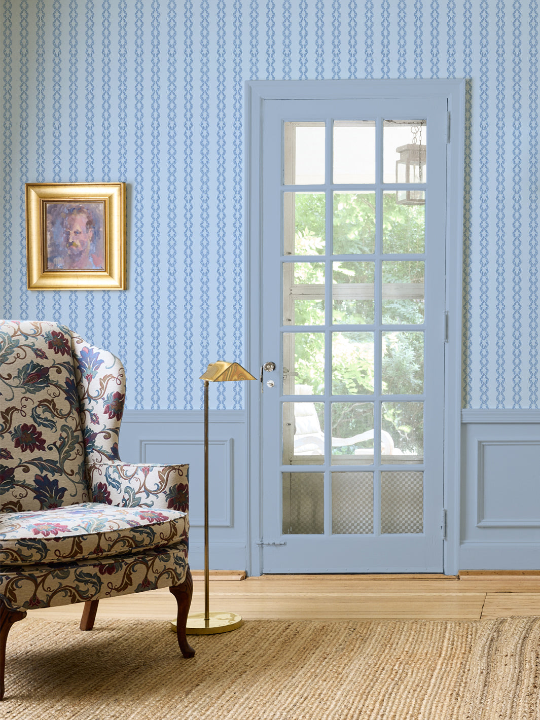 Soft Sky Sutton Vine wall with a floral wingback chair, brass floor lamp and blue French door